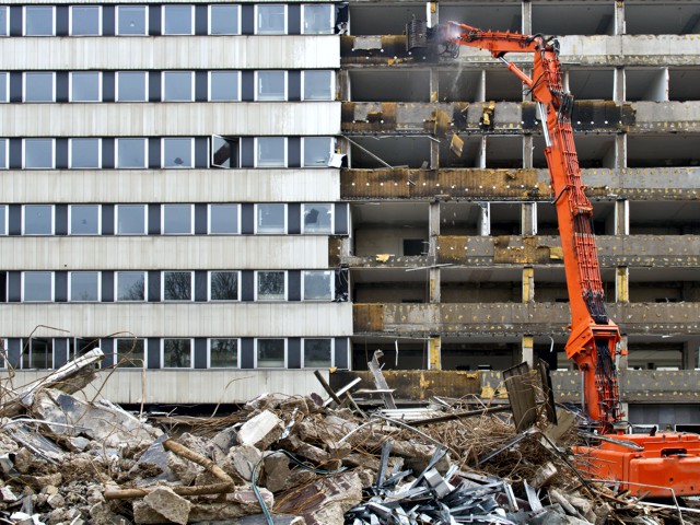 Abriss eines Hochhauses mit Bagger.